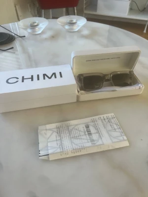 Gråa solglasögon från CHIMI - HELT OANVÄNDA Snygga gråa solglasögon från CHIMI med klassisk rektangulär form. Kommer med originalfodral, låda och kvitto. Perfekta för att lyfta din stil med en modern och stilren look. 