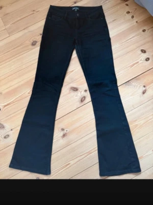 Svarta låga bootcut jeans från Pieces - Snygga svarta bootcut jeans från Pieces med klassisk femficksdesign och låg midja. Jeansen har utsvängda ben och är tillverkade i ett stretchigt denimtyg som sitter bekvämt. Perfekta för dig som gillar en tidlös och trendig look.