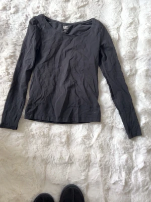 Svart långärmad topp från 157 - En enkel svart långärmad topp från 157 med rund halsringning. Tillverkad i mjuk bomull som känns skön mot huden. Den sitter tjight. Perfekt att styla lager på lager eller bära som den är. Klassisk och tidlös design som passar till det mesta.