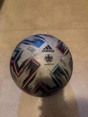 Adidas Euro 2020 fotboll - Säljer en officiell Adidas Euro 2020 fotboll i storlek 5. Bollen är vit med färgglada detaljer i svart, blått, rosa och gult. Perfekt för matcher eller träning. Klassisk design med Euro 2020-logga och Adidas-märke.