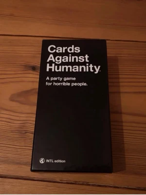 Cards Against Humanity INTL Edition - Säljer sällskapsspelet Cards Against Humanity, International Edition. Spelet kommer i en svart låda med vit text och innehåller en stor hög spelkort samt instruktioner. Perfekt för spelkvällar med vänner som gillar humor och utmanande frågor.