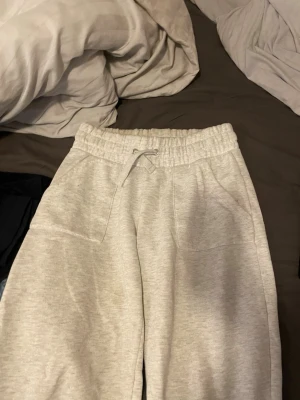 Grå mjukisbyxor - Säljer ett par ljusgrå mjukisbyxor med resår i midjan och dragsko. Byxorna har två fickor fram och två bakfickor. Tillverkade i mjukt sweatshirtmaterial som är perfekt för chill dagar. Passar dig som gillar en relaxed och enkel stil.