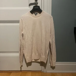 Merinoull tröja från Uniqlo - Snygg beige stickad tröja från Uniqlo i storlek S. Tröjan har rund hals och långa ärmar med ribbade muddar vid hals, ärmslut och nederkant. Perfekt för lager-på-lager och enkel att matcha med jeans eller chinos.