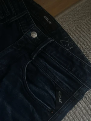 Mörkblå Replay jeans - Snygga mörkblå jeans från Replay med klassisk femficksmodell och diskreta slitningar. Jeansen har smal passform och är tillverkade i ett mjukt denimtyg. Perfekta för dig som gillar stilrena och bekväma jeans med en modern look. Endast använda ett fåtal gånger 