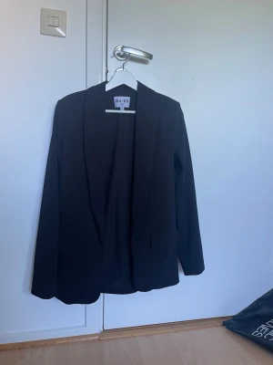 Svart kavaj från NA-KD - Med fickor och axelvaddar. Använd ett par gånger, mycket bra skick! Passar även storlek 34/XS