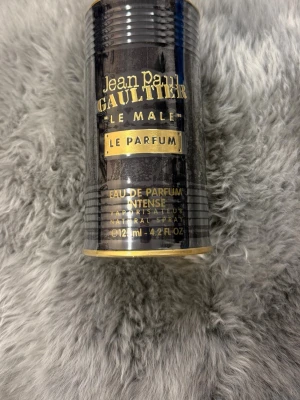 Jean Paul Gaultier Le Male Le Parfum - Jean Paul Gaultier Le Male Le Parfum Eau de Parfum Intense i en svart och guld cylinderformad metallförpackning. Flaskan rymmer 125 ml och har en maskulin design med guldiga detaljer. En ikonisk doft för dig som gillar exklusiva parfymer. Obs - oöppnad
