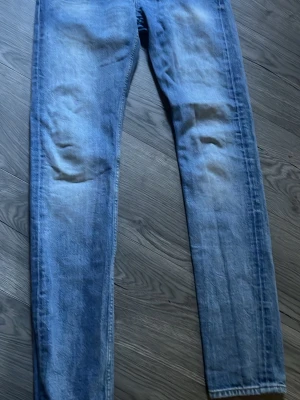 Blå slim fit jeans med tvättade detaljer - Säljer ett par blå slim fit jeans med snygga tvättade detaljer och lätt slitna partier på låren och knäna. Jeansen har klassisk femficksdesign och smal passform hela vägen ner. Perfekta till en avslappnad look.