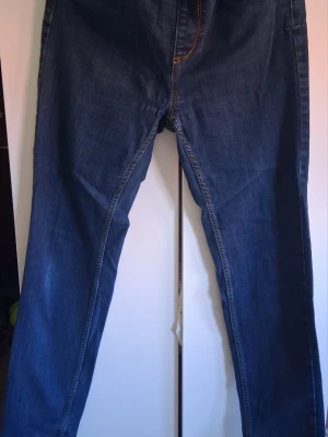 Mörkblå raka jeans med kontrastsömmar - Säljer ett par mörkblå jeans med raka ben och klassiska kontrastsömmar. Jeansen har två bakfickor och en enkel design utan synligt märke. Materialet är denim i bomull och passformen är avslappnad men ändå stilren. I strechigt material
