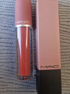 MAC Brave flytande läppstift rosa - MAC Brave är ett flytande läppstift i en mjuk, dammigt rosa nyans. Kommer i en elegant cylinderformad tub med matt rosa lock och genomskinlig kropp som visar färgen. Förpackningen är matchande rosa med svart botten och MAC-logga.