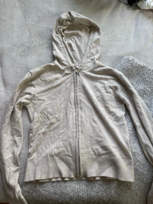 Beige hoodie med dragkedja - Ljusbeige hoodie med dragkedja framtill och huva med snören. Tillverkad i ett tunt, mjukt material.