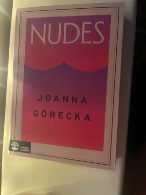 Nudes av Joanna Górecka - Romanen 'Nudes' av Joanna Górecka har ett omslag i rosa och lila toner med stilren design. Boken är utgiven av Natur & Kultur och handlar om vänskap, identitet och att växa upp. Perfekt för unga vuxna som gillar samtida skönlitteratur.