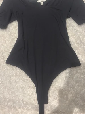 Svart body med kort ärm - En svart body från H&M med korta ärmar och rund halsringning. Jätte mysigt material💘 Säljer även en i vit
