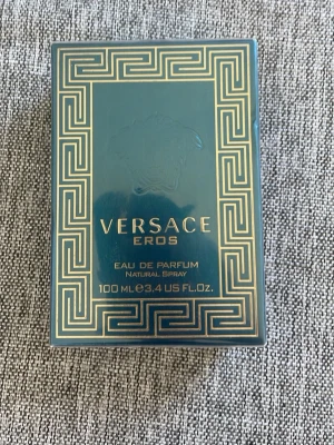 Versace Eros Eau de Parfum 100ml - Versace Eros Eau de Parfum i en lyxig blågrön och guldig förpackning. Flaskan rymmer 100 ml och har en elegant design med klassiska Versace-detaljer. Perfekt för dig som gillar exklusiva och kraftfulla dofter.