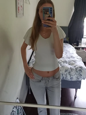 Vit ribbad croppad topp - Snygg vit croppad topp med v-ringning och korta ärmar. Toppen är ribbad och har en figurnära passform som framhäver midjan. Perfekt att matcha med jeans eller kjol för en trendig look.