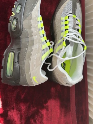 Nike  Air Max 95 Neon sneakers - Nike Air Max 95 sneakers i grått och vitt med neongula detaljer och synlig Air-dämpning i sulan. Skorna har meshpaneler för bra ventilation, svarta och grå partier samt vita skosnören. Klassisk retrostil med ikonisk design och bekväm passform. Aldrig använt 