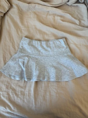Ljusgrå kortkjol i bomull - Enkel och snygg ljusgrå kortkjol i mjuk bomull med utsvängd form. Perfekt att matcha med en crop top eller hoodie för en avslappnad look.
