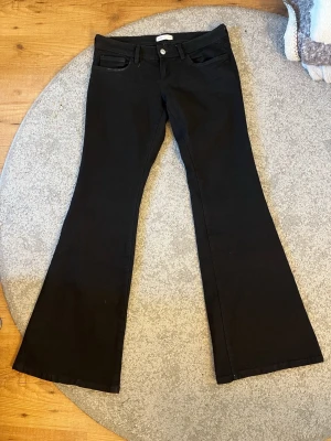 Svarta bootcut jeans - Snygga svarta bootcut jeans med klassisk femficksdesign och utsvängda ben. Jeansen har låg midja och stängs med knapp och dragkedja. Aldrig använda, dock är lappen inte kvar