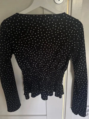 Svart prickig blus från Gina Tricot - Supersöt svart blus med vita prickar från Gina Tricot. Blusen har lång ärm, smockad midja och volangkant nedtill. Perfekt för dig som gillar en feminin och trendig look. Tunt och lätt material som känns skönt mot huden. Är i nyskick men har ej kvar prislapp, säljer då den va för liten för mig!💓Pris kan diskuteras, bara att skriva vid frågor/annat