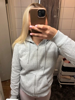 Grå hoodie - Ljusgrå zip-hoodie från Tommy Hilfiger. Hoodien har ett mjukt material inuti som man kan se på bilderna😊