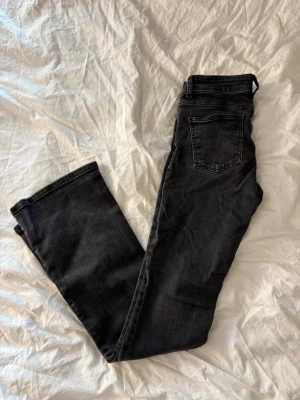 Svarta jeans från 157, raka ben - Snygga svarta jeans från 157 med raka ben och klassisk femficksdesign. Jeansen har en mörk tvätt och silverfärgade nitar vid fickorna. Perfekta för en stilren och avslappnad look.