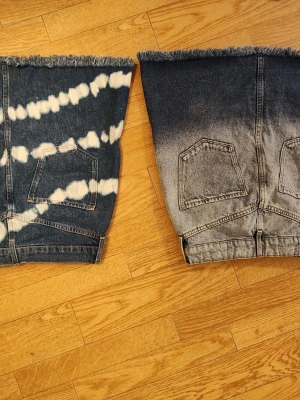 Två jeanskjolar med fransig kant tjej stl 170 - Säljer två coola jeanskjolar i kort modell. Ena kjolen har ett batikinspirerat mönster i blått och vitt, medan den andra har en tvättad gråblå look. Båda har fransig kant nedtill och klassiska fickor både fram och bak. Perfekta för dig som gillar unik denimstil. Nya, endast provade och tvättade. Båda i tjej storlek 170 och har justerbar resår i midjan.