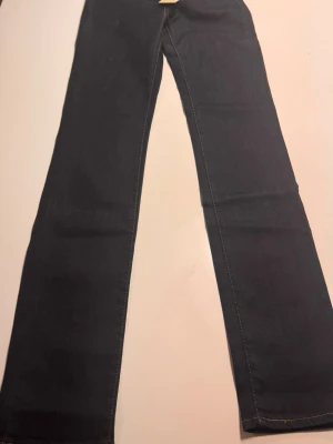 Mörkblå Levi's bootcut jeans - Säljer ett par mörkblå bootcut jeans från Levi's med klassiska kontrastsömmar och femficksdesign. Jeansen är i 100% bomull och har en snygg vintagekänsla med Levi's logga på knappen och etikett. Perfekta för dig som gillar tidlös denimstil.