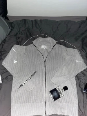 Grå stickad ziptröja Maison Margiela - Feeet Maison Margiela full zip knit. Aldrig använd och i skit bra kvalité. Super bekväm. Storlek M