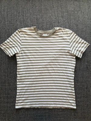 Randig T-shirt ~ sällsynt modell (selected) - Sjukt clean randig Selected-T-shirt i vit och khaki – stl L men passar M bäst. Skön passform och enkel att styla till vardag 🌿liten defekt bild visas  Fint skick och sitter riktigt bra ✌️ Perfekt till en clean outfit Kan även gå ner lite i pris vid snabb affär Skickas inom 24h 📦