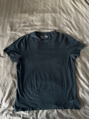 Mörkblå t-shirt från Jacob Cohën - Snygg mörkblå t-shirt från Jacob Cohën med diskret logga broderad vid halsen. Klassisk rund halsringning och korta ärmar. Tillverkad i mjuk bomull som känns skön mot huden. Perfekt basplagg för en clean och stilren look. Storlek L men passar även M