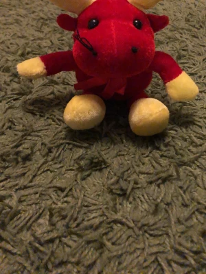 Röd och gul mjukisdjur ren - Söt mjukisdjur i form av en ren med röd kropp och gula horn, tassar och mule. Tillverkad i mjuk plysch och har svarta ögon samt en liten rosett runt halsen. Perfekt som dekoration eller gosedjur.