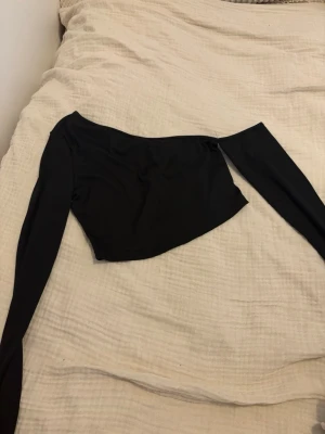 Svart oneshoulder topp från shein  - Snygg svart oneshoulder topp med lång ärm på ena sidan. Croppad modell som ger en trendig look. Perfekt för dig som vill sticka ut med en asymmetrisk stil. Tillverkad i mjukt och stretchigt material för skön passform. Använts ett fåtal gånger, kom med egna bud eller kontakta mig vid intresse 