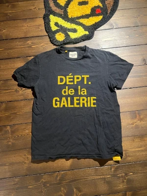 Svart t-shirt från Gallery Dept. - Svart t-shirt från Gallery Dept. med stor gul text 'DÉPT. de la GALERIE' på framsidan. Köpt i Gallery adept affären i Miami. Ny pris är 2700