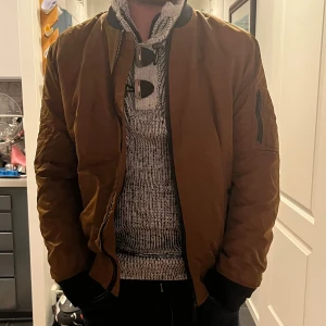 Brun bomberjacka från Calvin Klein - Snygg brun bomberjacka från Calvin Klein med svarta muddar och detaljer. Jackan har dragkedja framtill, ficka med dragkedja på ärmen och klassisk ribbad krage. Skriv vid frågor eller pris! Inga defekter 