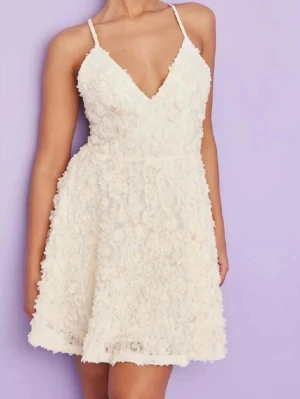 Vit kort klänning med blommor från Ida Sjöstedt i modellen ”Charlie dress” - Supersöt vit kort klänning med tunna axelband och djup v-ringning från Ida Sjöstedt❣️Klänningen är täckt av 3D-blommor som ger en unik och romantisk look. Perfekt för sommarens alla tillfällen och har en lätt utsvängd kjol för extra rörelse. Modellen är ”Charlie dress” i en krämvit/ vit färg! Nypris 3799kr och priset kan diskuteras! Skriv för egna bilder 