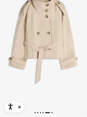Kort beige trenchcoat med bälte - Säljer denna slutsålda trench coat i storlek S, helt oanvänd med prislappar kvar. ❤️