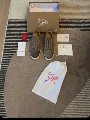 Loubs! - Snygga gråa sneakers från Christian Louboutin i mocka och klassisk låg profil. Skorna har rund tå, ton-i-ton snörning och diskreta sömdetaljer. Perfekta för dig som vill ha en stilren och exklusiv look.