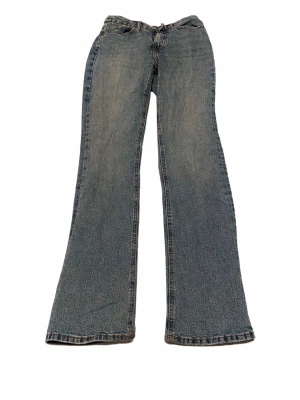 Blå bootcut jeans med utsvängda ben - Säljer ett par klassiska blå bootcut jeans med utsvängda ben och femficksmodell. Jeansen har en snygg tvättad look och normal midja. Perfekta för dig som gillar retrostil och vill ha ett par bekväma jeans i slitstarkt denimtyg.