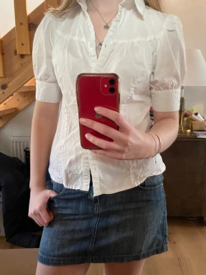 Vit kortärmad blus med krage - Snygg vit blus med korta puffärmar och klassisk krage. Blusen har knäppning framtill och är lätt figursydd för en feminin siluett. Perfekt att matcha med jeans eller kjol till våren💕💕