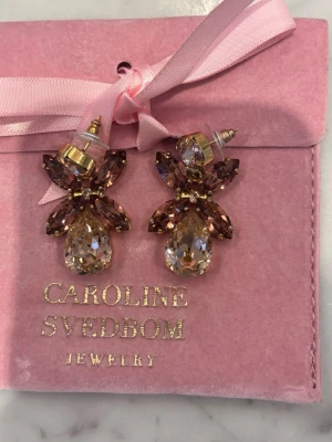 Mini Dione Caroline Svedblom örhängen - Så fina örhängen perfekta till fest och middagar🥰 Guldfärgad med stenar i rosa/beige och röd/brun🩷🩷 Exklusiv färg som inte säljs längre De är min mammas och köpta för några år sedan så vet tyvärr inte vad färgen heter Sista bild för storleks referens