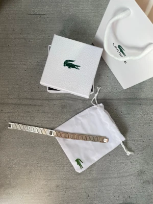 Lacoste Armband - Snyggt armband från Lacoste i ny skick. Stilren design som passar till allt. Perfekt för både vardag och finare tillfällen.