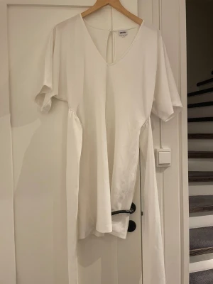 Vit omlottklänning från Bubbleroom - Säljer en vit omlottklänning från Bubbleroom i storlek 32. Klänningen har v-ringning, korta ärmar och långa knytband i midjan för en snygg siluett. Perfekt för dig som gillar minimalistisk och stilren design.