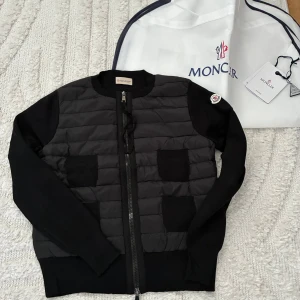 Svart cardiganjacka från Moncler - Snygg svart cardiganjacka från Moncler. Perfekt jacka till våren. Fortfarande i nyskick då den inte kommit till användning. Storlek L men passar en M perfekt. Kvitto finns. 