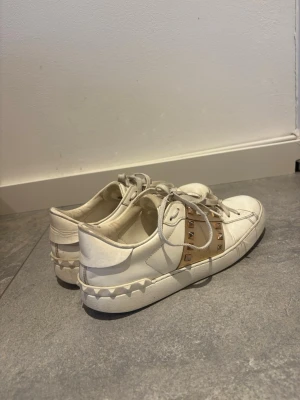 Valentino sneakers - Säljer ett par jätte fina valentino sneakers med guld/rosé guld linje och nitar. Jättefina och passar till allt! Storlek 41/40. Kartong och dustbag följer med!