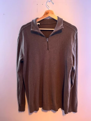 Brun halvzip tröja med krage - Mjuk brun långärmad tröja med halv dragkedja och hög krage. Tröjan har en enkel och clean design utan synliga loggor eller mönster. Perfekt för lager på lager och passar till det mesta. 