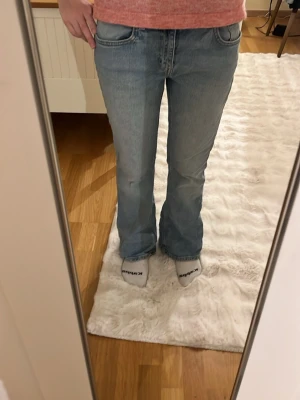 Ljusblå bootcut jeans - Säljer ett par ljusblå bootcut jeans med klassisk femficksdesign och normal midja. Jeansen har en avslappnad passform och är tillverkade i mjukt denimtyg. Perfekta för en chill och trendig look. I storlek S short 