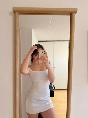 Vit offshoulder strand klänning - Säljer en vit, kort strand klänning med offshoulder- figurnära passform. Fin till sommaren under bikinin med tan 😍