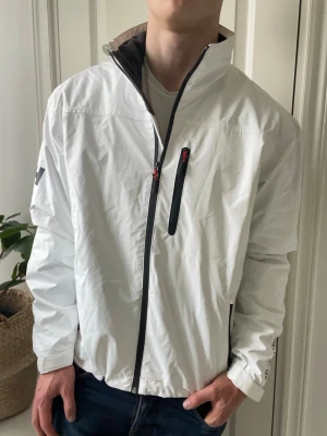 Helly Hansen vind jacka  - Helly Hansen vind jacka vit, väldigt stor på modellen, Inga defekter förutom några små märken som ni ser! Modellen i bilderna är 180 cm 75 kg och bär Storlek L, Kom med frågor! 🌟 (Kan gå ned i pris vid köp av paket 😉) 