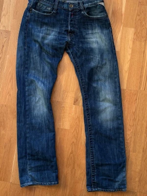 Blå raka Replay jeans med slitningar - Säljer ett par riktigt sköna Replay jeans i färgen blå,  med raka ben och snygga slitningar på låren och knäna. Perfekta för en avslappnad och trendig look.