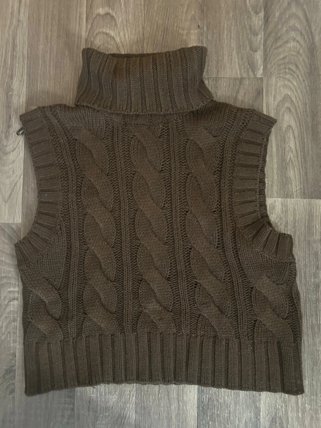 Brun stickad poloväst med flätmönster