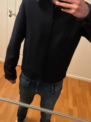 Svart Overshirt med zip  - Säljer en svart overshirt från Selected Homme med klassisk krage och hel dragkedja framtill. Jackan har långärmade ärmar och diskreta sidofickor. Perfekt för dig som vill ha en stilren och enkel look.